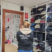 Policial civil junto a itens de roupas em uma sala 