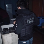 Policial civil com identificação de Polícia Civil DEIC fiscalizando caixa térmica branca
