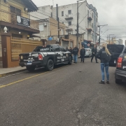 Veículos da Polícia Civil e policiais andando em rua em frente à Delegacia