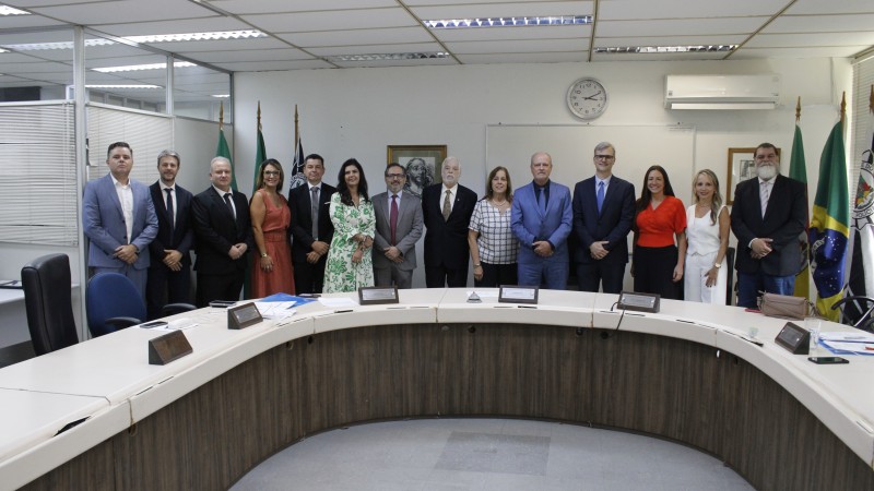 Pessoas em p&eacute; perfiladas lado a lado atr&aacute;s de uma mesa aredondada