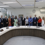 Pessoas em p&eacute; perfiladas lado a lado atr&aacute;s de uma mesa aredondada