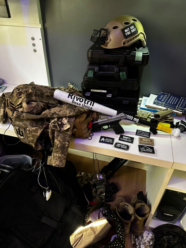 Capacete e roupas militares, além de outros materiais apreendidos sobre mesa e ao chão