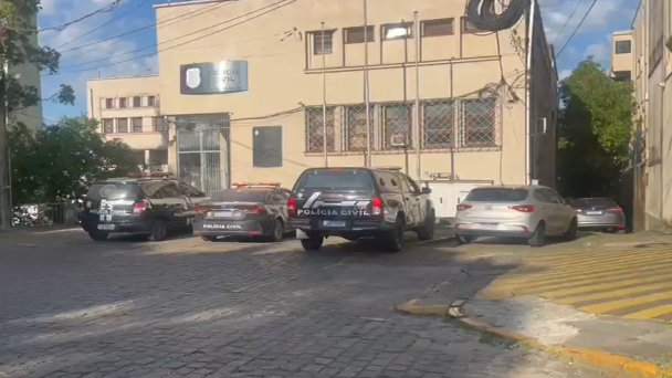 Viaturas policiais estacionadas em frente a um pr&eacute;dio de colora&ccedil;&atilde;o bege sede de Delegacia de Pol&iacute;cia